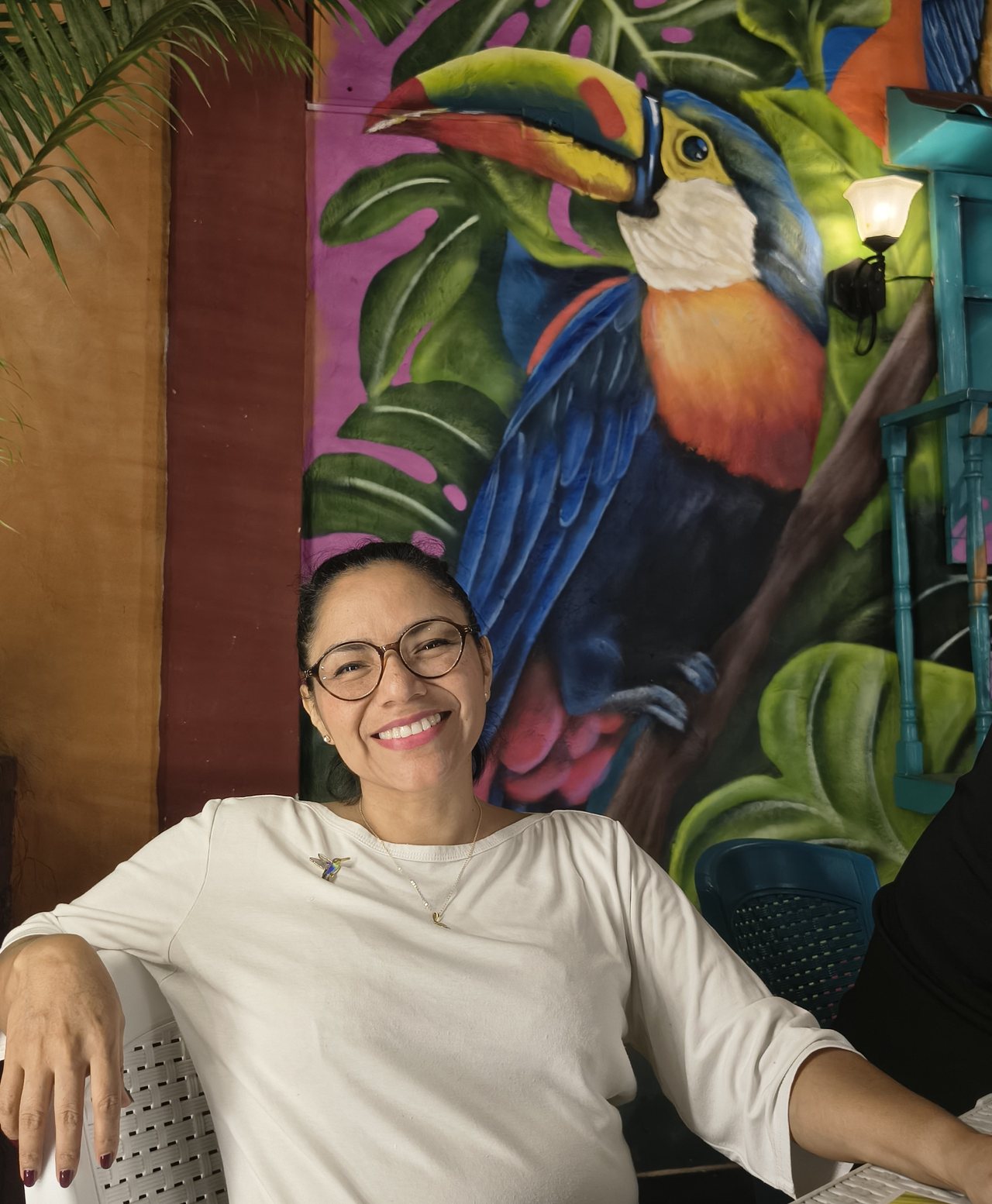 Mara Gabriela Fidelak, coach de desarrollo personal en Clarum Coaching, frente a un mural con un tucán